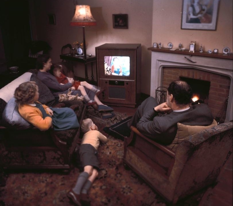 Family of four watching television in a vintage living room setting