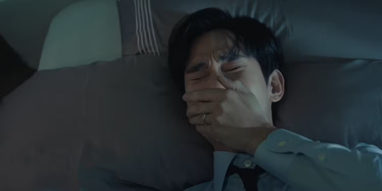 Hombre llorando y cubriendo su boca con la mano en un ambiente oscuro