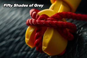 Close-up of a red rope tied in a knot around a LEGO hand, with "Fifty Shades of Grey" text overlay