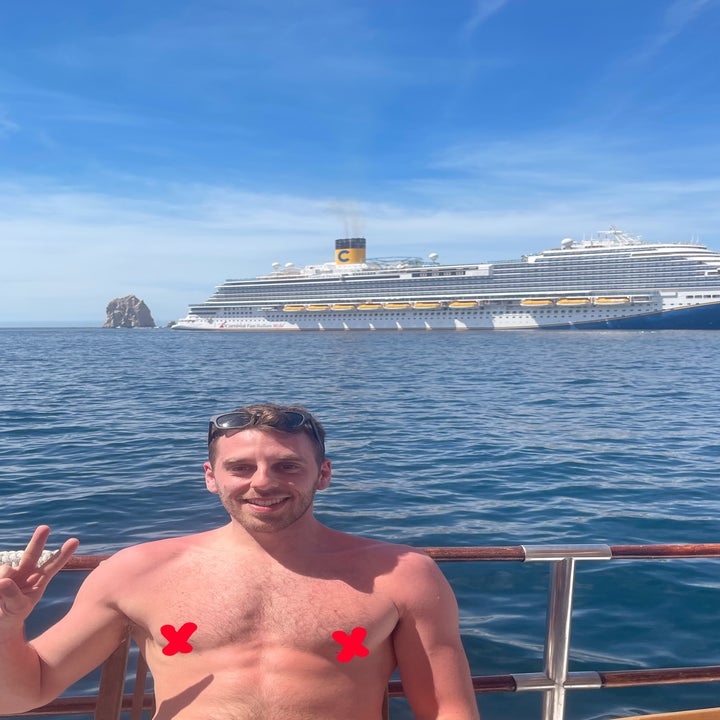Man giving a peace sign on a boat with a cruise ship in the background