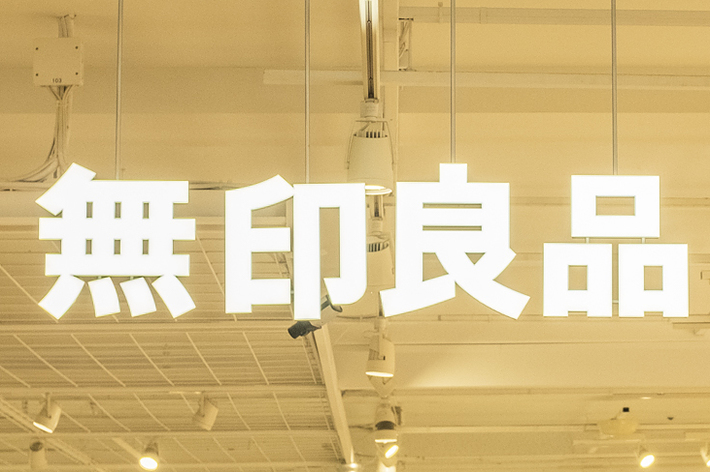 店内に人々がいるスーパーマーケットで、看板に「無印良品」と書かれています。