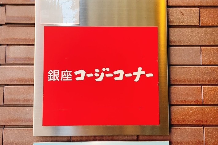Sign in Japanese on a red background mounted on a brick wall