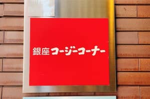 Sign in Japanese on a red background mounted on a brick wall