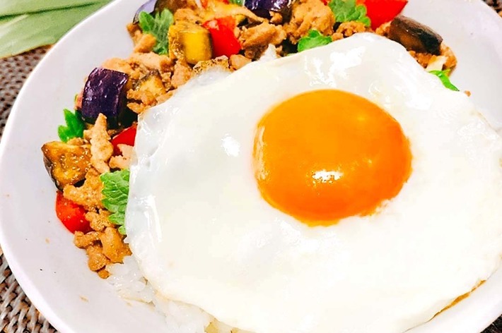 ご飯の上に目玉焼きと野菜と肉が乗った料理です。