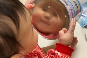 赤ちゃんが鏡を見ている。鏡にはテキストがあるが、読めない。服は赤白チェック柄です。