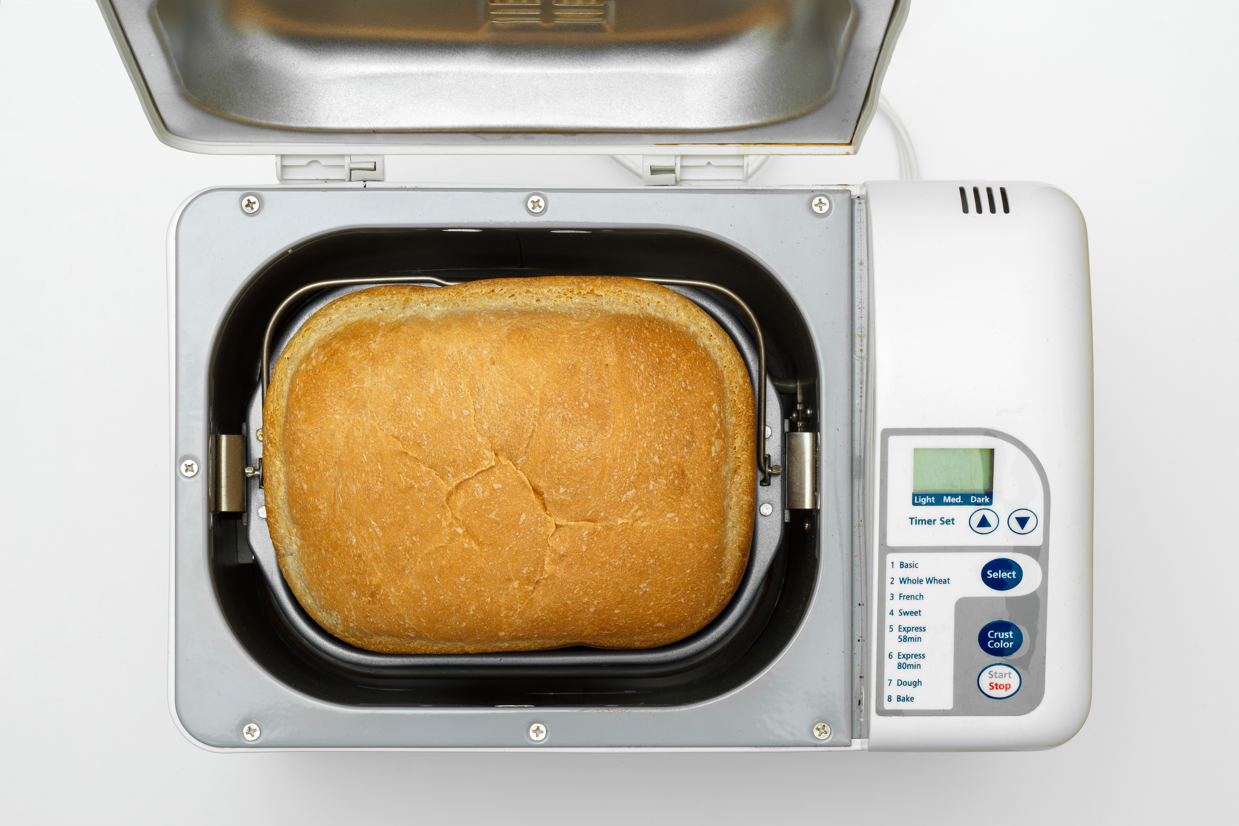 A freshly baked loaf of bread inside an open bread machine with a digital display