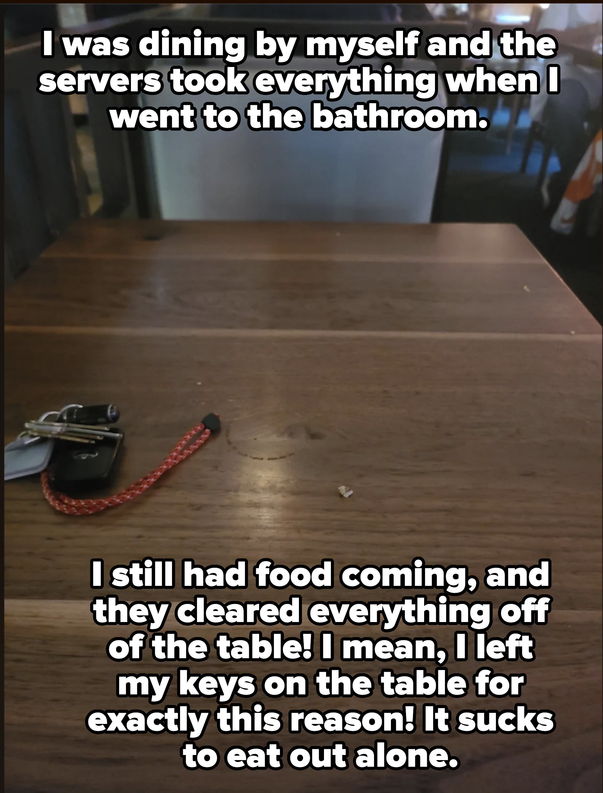 Car keys with a red lanyard on a wood table in a dimly lit room