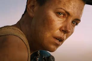 Close-up of a character, played by Charlize Theron, with an intense look and dirt on face