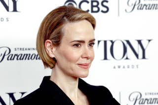 Side-by-side images of actress Sarah Paulson in two different outfits, one in formal attire with a bow accessory, and one in a plaid shirt