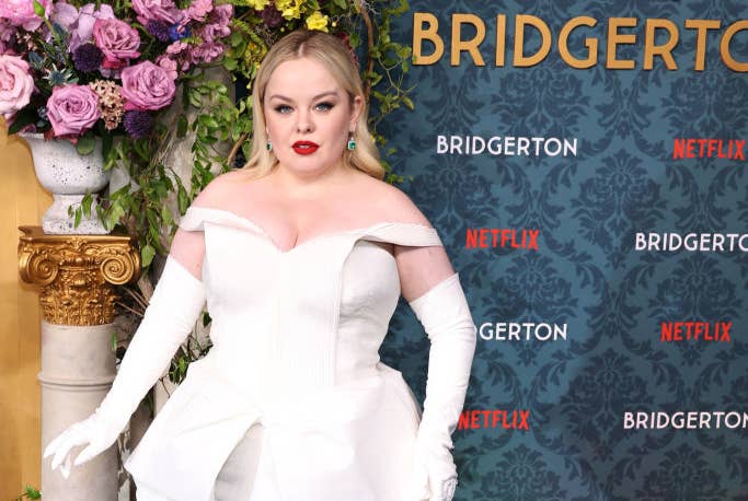 Nicola Coughlan posing in an elegant off-the-shoulder gown with structured details and gloves at the 'Bridgerton' Netflix event