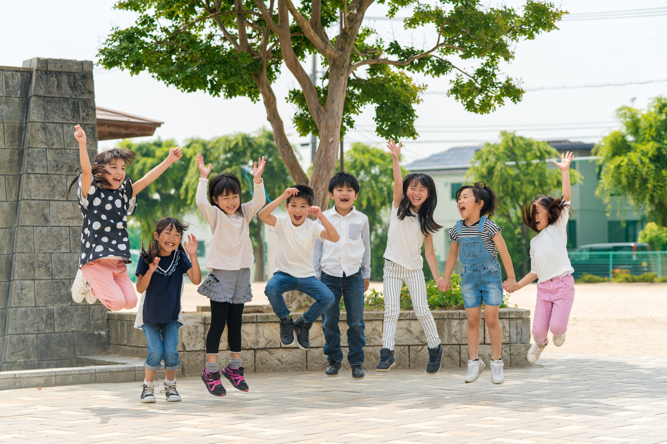 Group of children joyfully jumping in the air at a park, expressing freedom and happiness, signifying the joys of travel