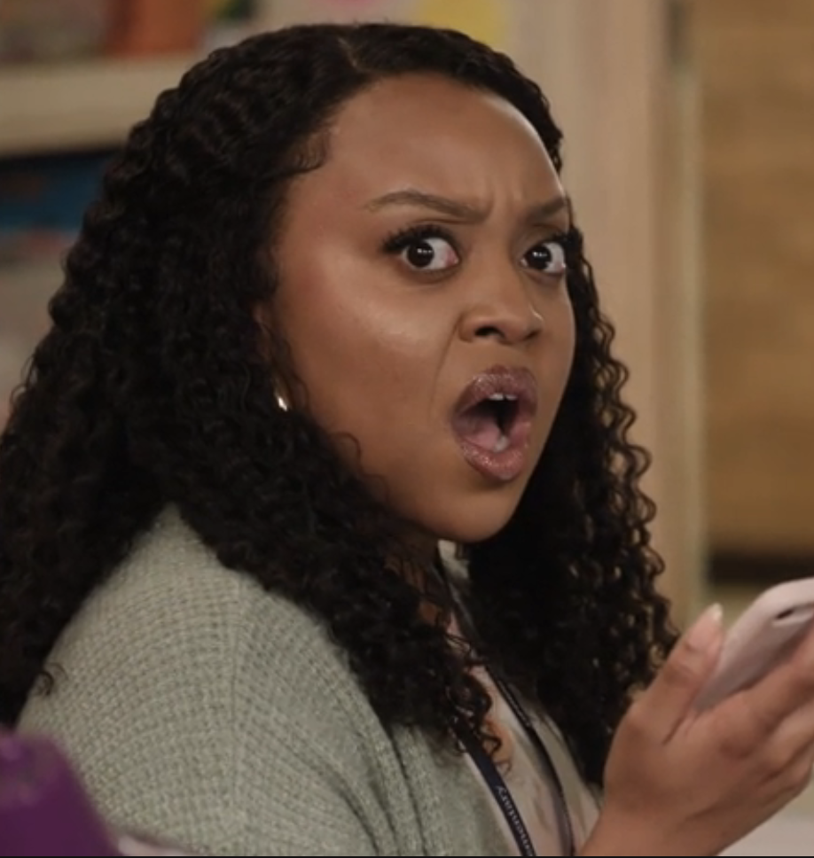 Woman with braided hair appears shocked while holding a phone