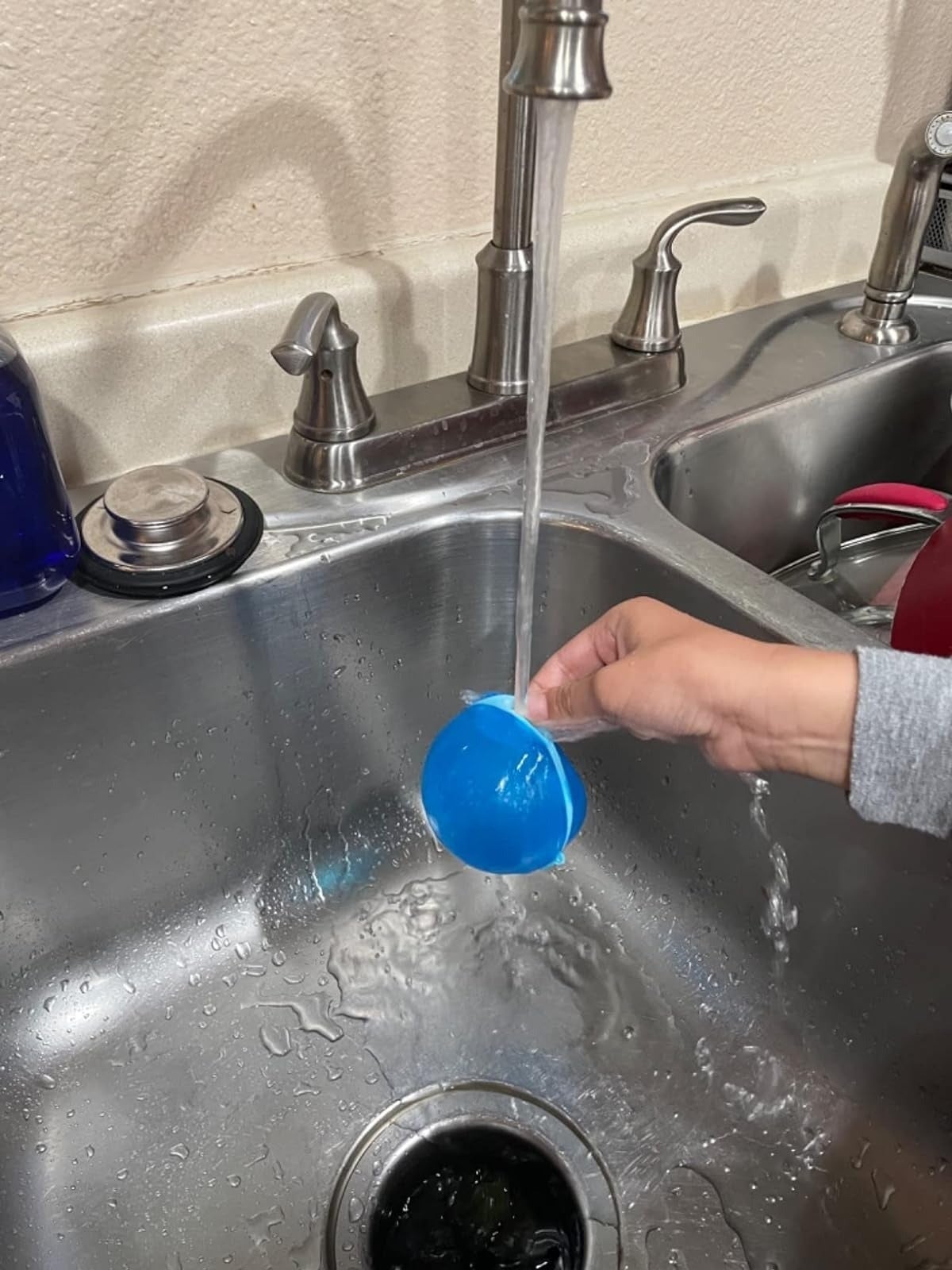 A idiosyncratic   refilling a reusable h2o  balloon successful  a sink