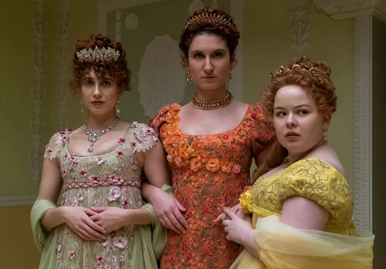Tres personajes de &quot;The Gilded Age&quot; en vestidos de época con detalles florales y joyería, posando con expresión seria