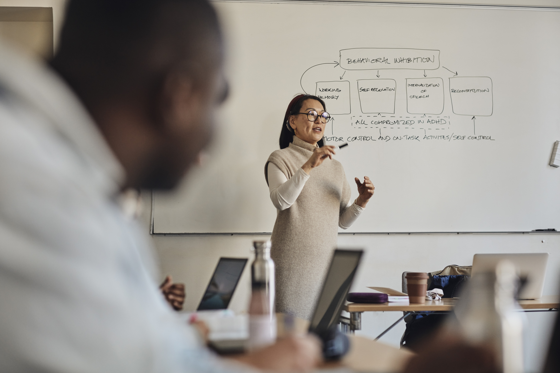 Professor presenting at a whiteboard during class, with students in foreground