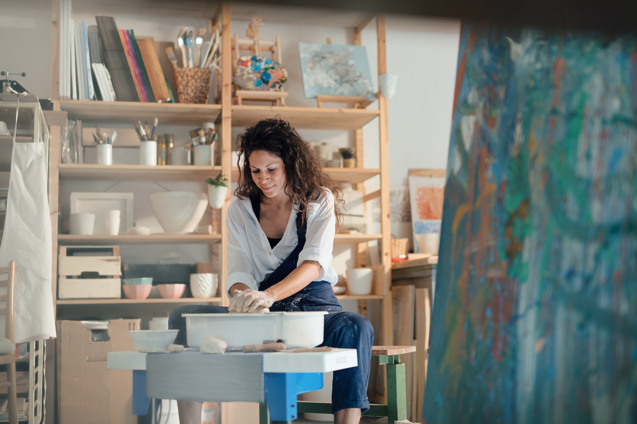 Woman shaping clay on a pottery wheel in an art studio