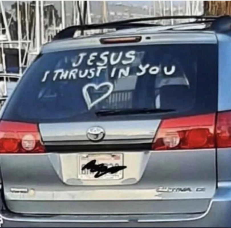 Dusty car with "JESUS I THRUST IN YOU" written on the rear window