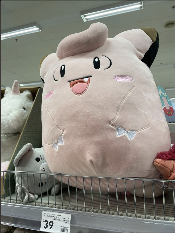 Large plush toy of Clefairy, a Pokémon, on a store shelf with other toys