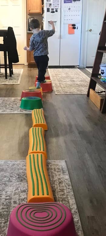 Child balancing connected colorful stepping stones successful a kitchen, practicing coordination and play successful a location setting