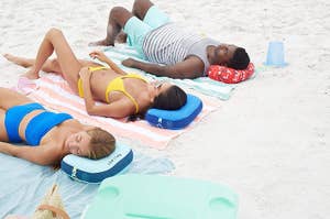 three models lying on the pillows at the beach