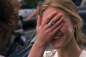 Woman smiling with hand covering face wearing a ring, from a film scene