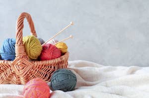 かごに入った編み物用の毛糸と編み棒がある。