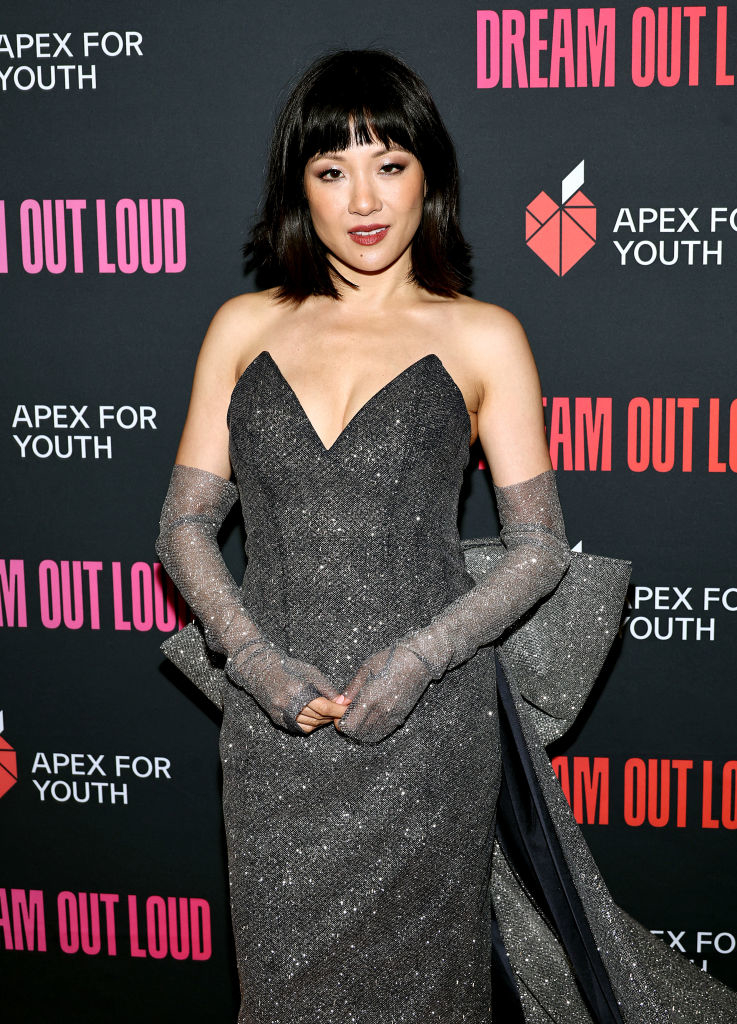 Constance Wu in a glittery dress with a sweetheart neckline and long gloves at an event