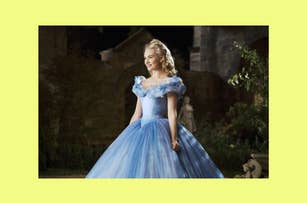 Lily James as Cinderella, wearing a blue gown with sheer sleeves, standing in a garden setting