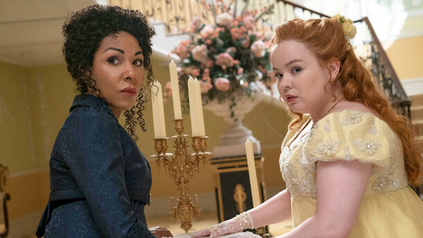 Dos personajes de 'Bridgerton', una vestida de amarillo con guantes y la otra de azul oscuro. Escena de época en interior elegante