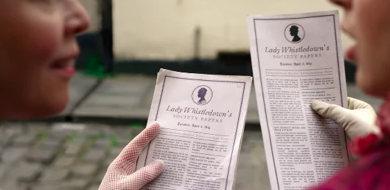 Dos personas sostienen "Lady Whistledown's Society Papers" enfocados sobre un fondo borroso