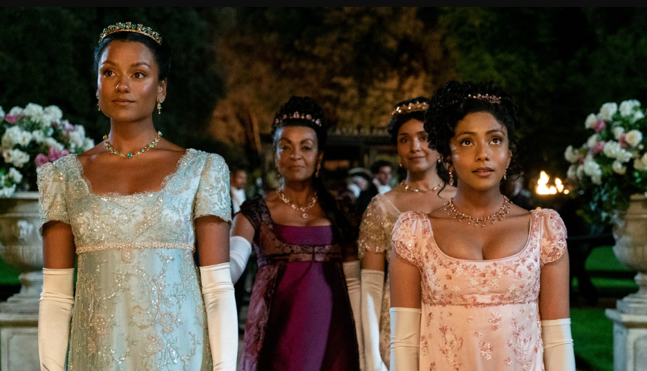 Cuatro personajes femeninos de "Bridgerton" con vestidos de época en un evento nocturno al aire libre