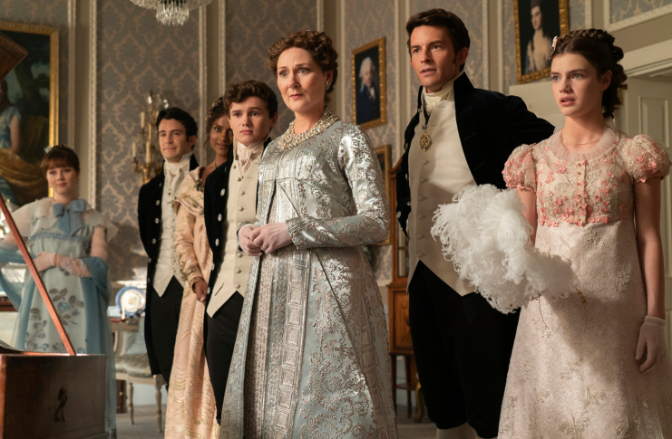 Personajes de época vestidos elegantemente en una sala, posiblemente de una película de ambiente histórico