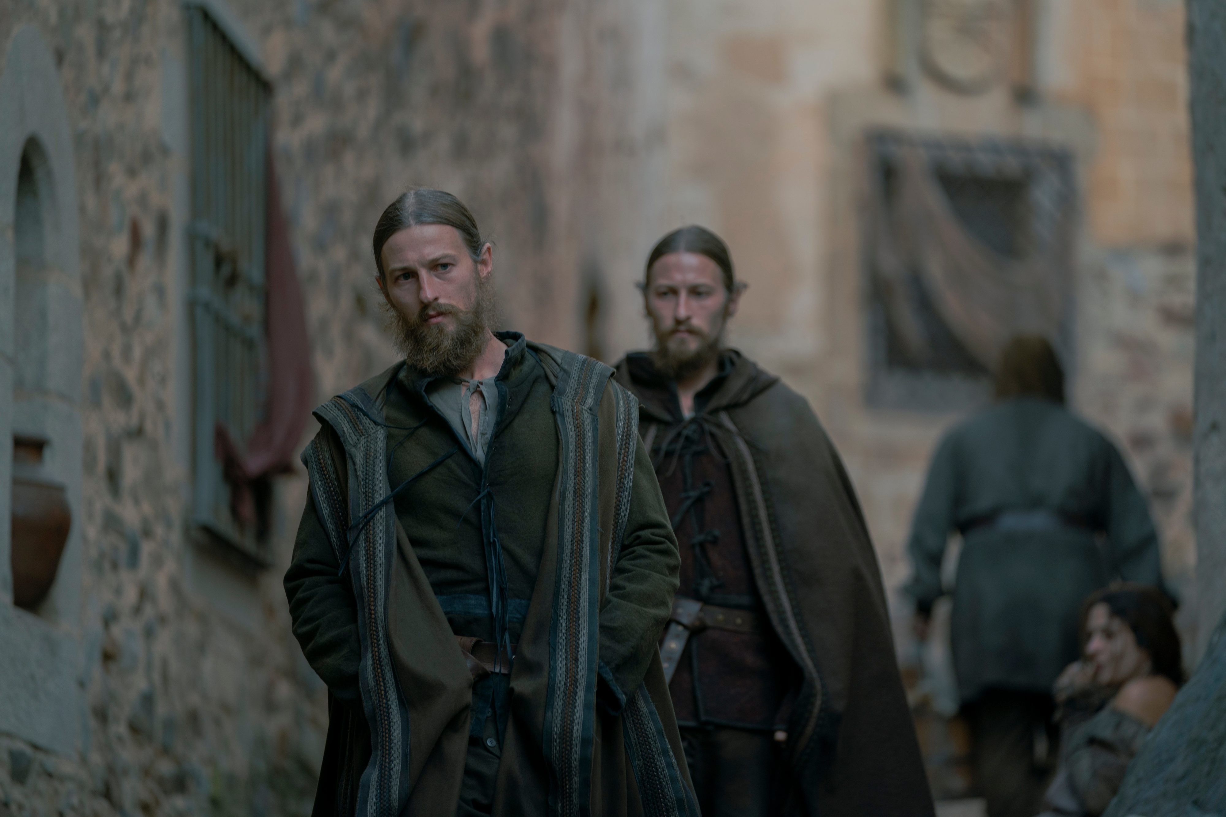 Personajes de ficción con ropas medievales en un ambiente de época, mirando seriamente hacia adelante