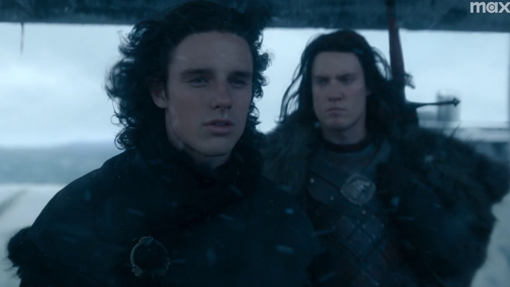 Dos personajes de ficción vestidos con ropas de estilo medieval miran seriamente hacia delante en un entorno nevado