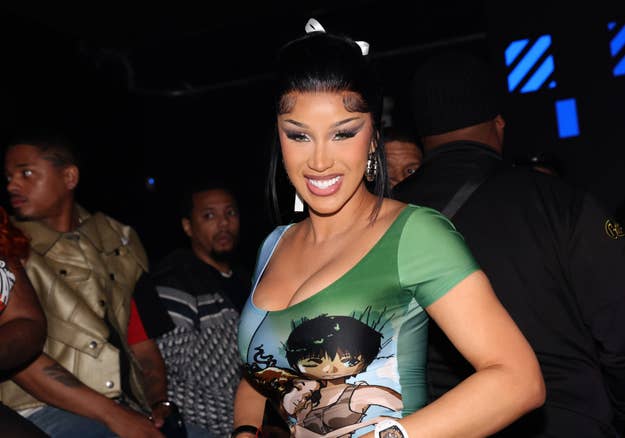 Cardi B at event wearing a graphic tee with an anime character, accessorized with a bow in their hair