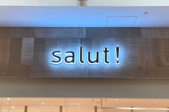 店舗の入口上部に「salut!」と発光するサインがあります。