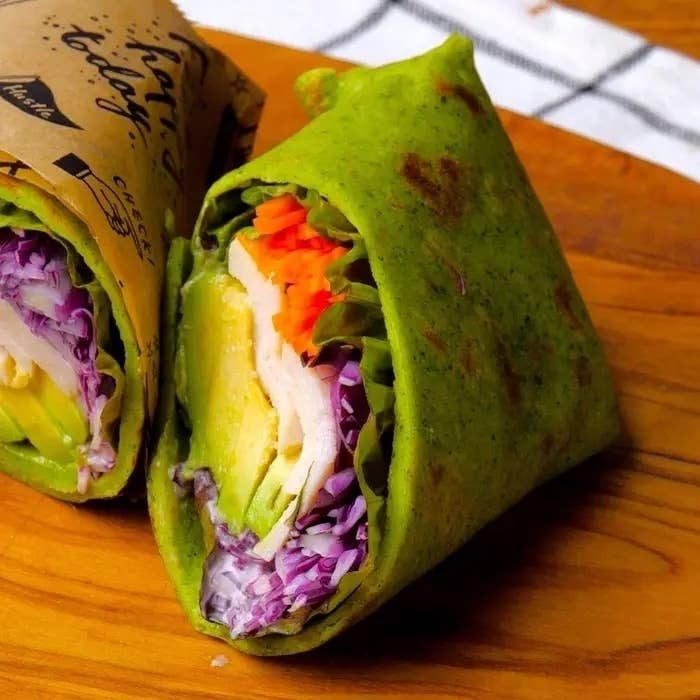 野菜がたっぷり入り、折りたたまれたグリーンのラップサンドイッチ。