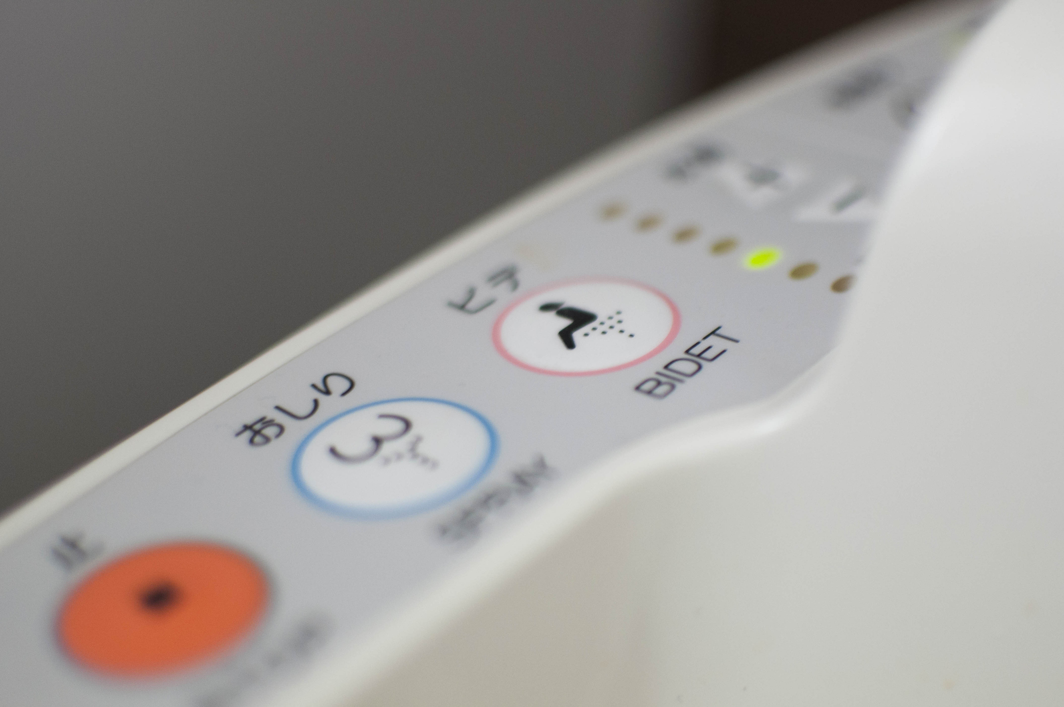 Control panel of a bidet with buttons for various functions, close-up shot