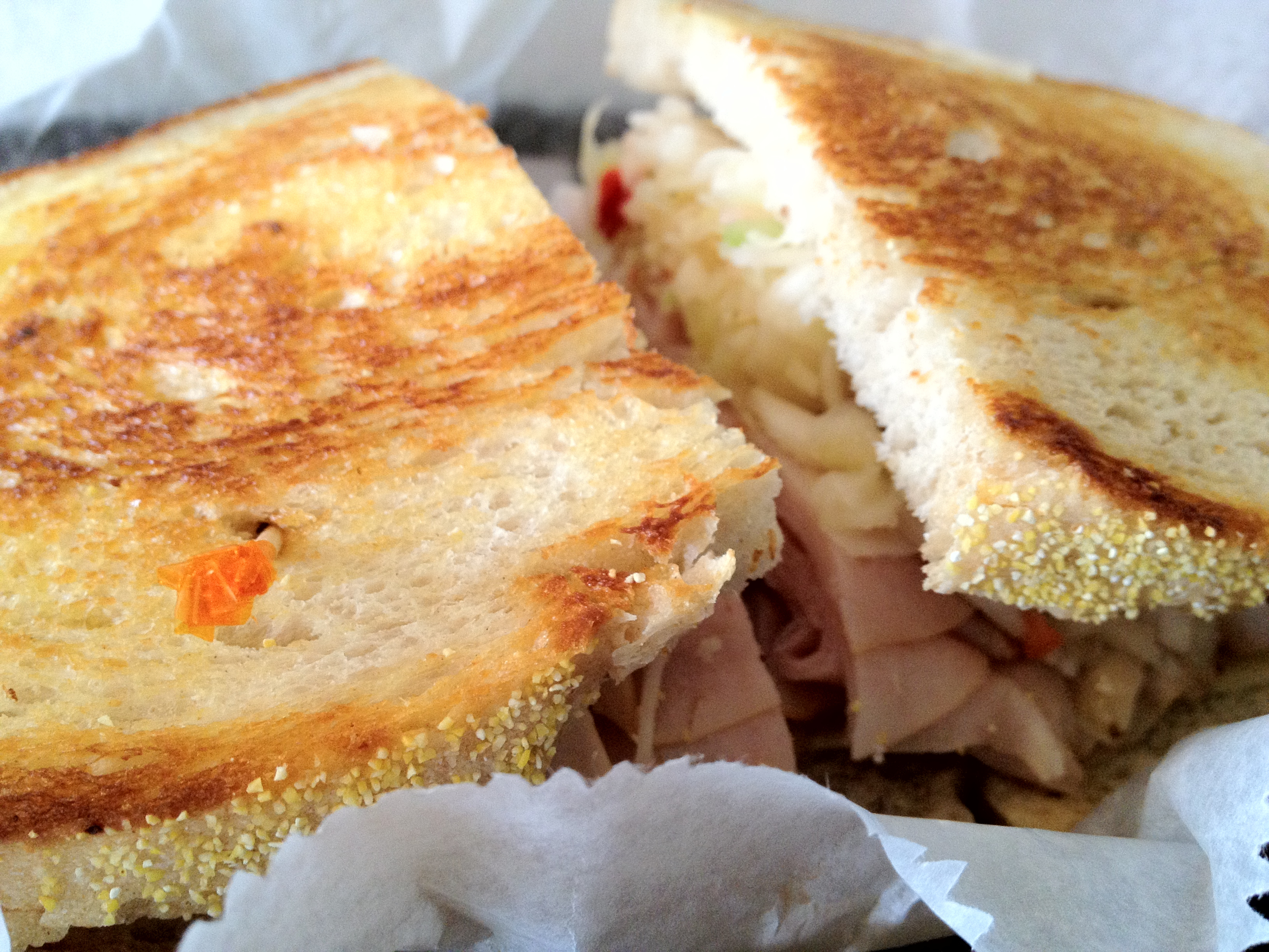 A turkey sandwich with lettuce and tomato on toasted bread, cut in half on a paper-lined tray