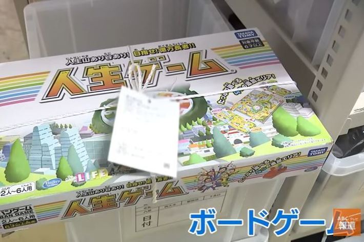 テーブルゲームの箱と上に置かれた紙コップが写っています。