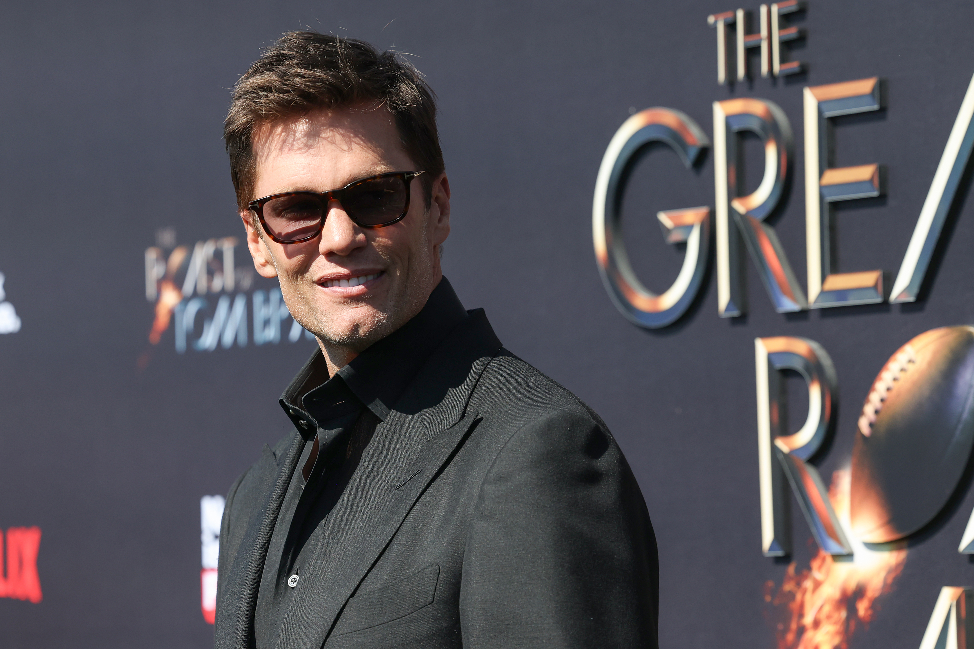 Tom Brady in a dark suit and sunglasses posing at a &#x27;The Great Race&#x27; event