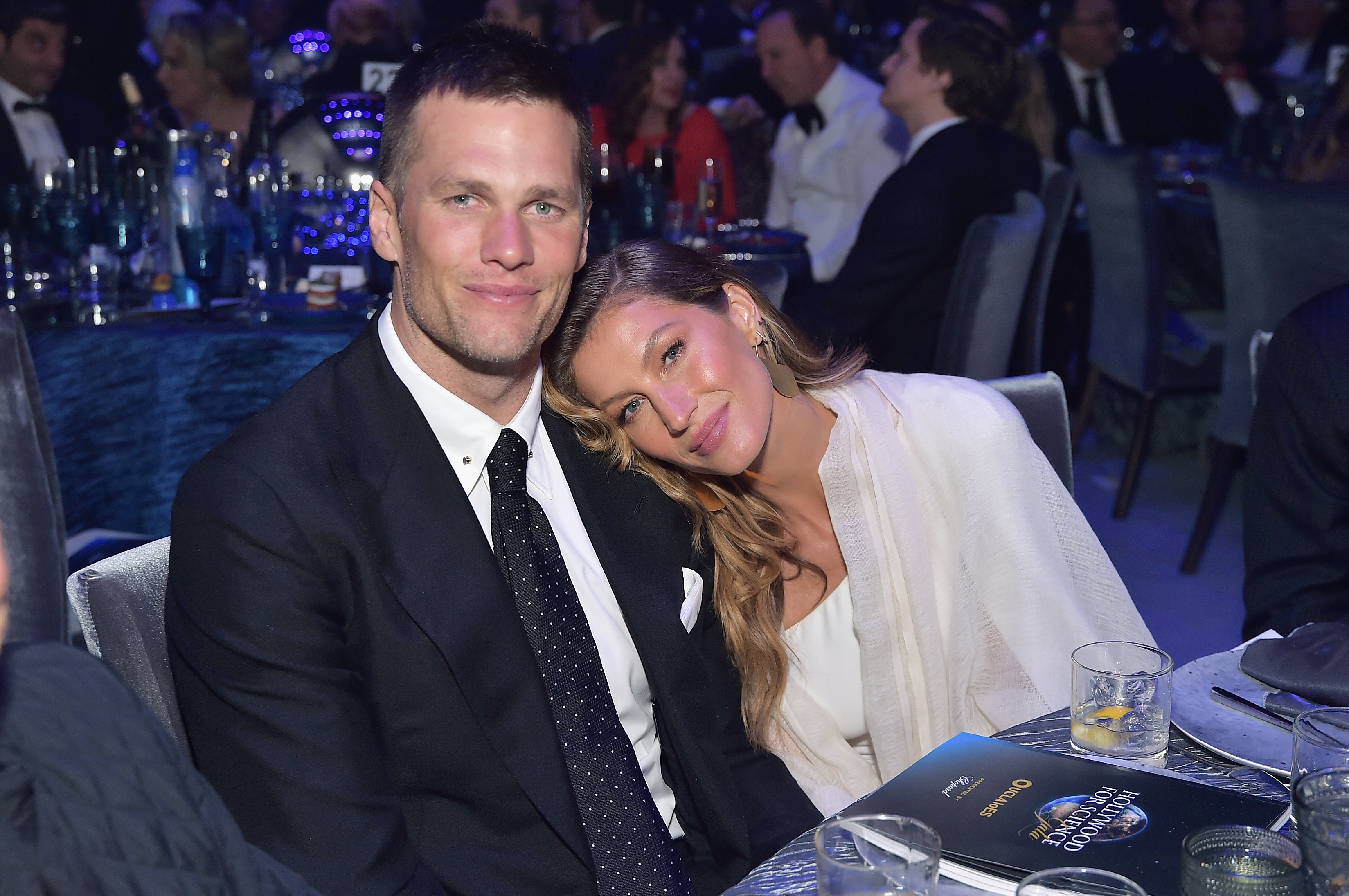 Gisele and Tom sitting at a table at an event