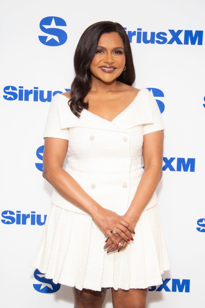 MIndy in a V-neck dress posing in front of SiriusXM backdrop