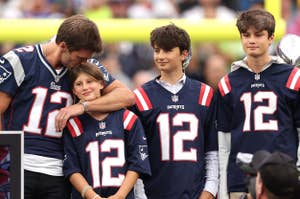 Tom Brady with three children in Patriots jerseys at a football stadium