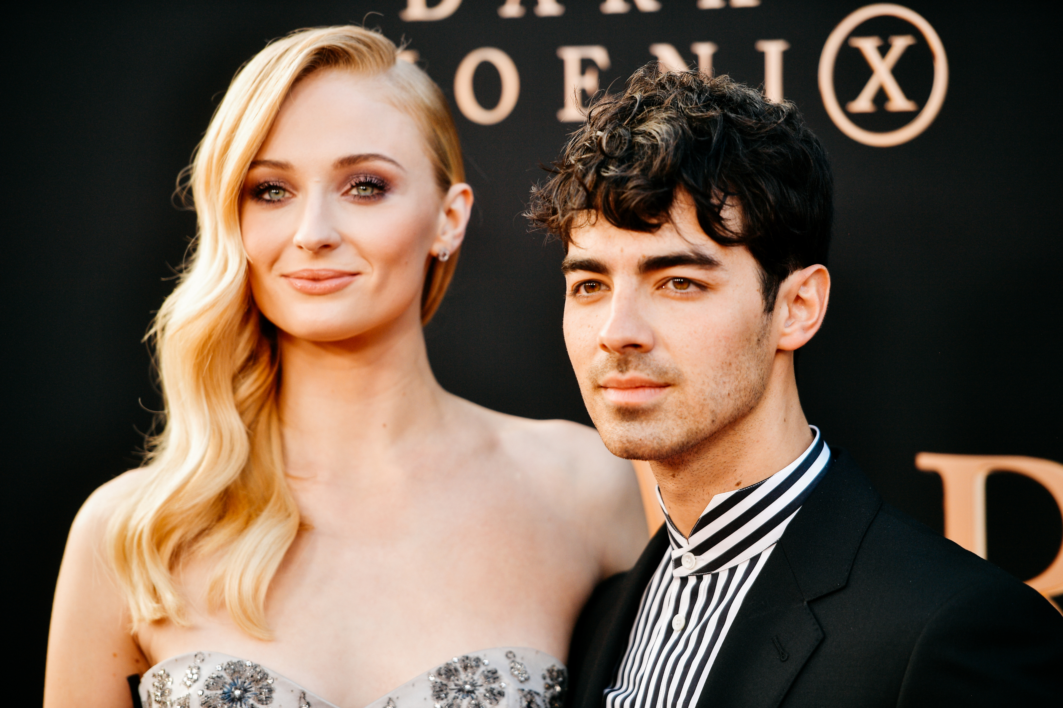 Sophie Turner in a glittery strapless dress with Joe Jonas in a striped suit, posing at an event