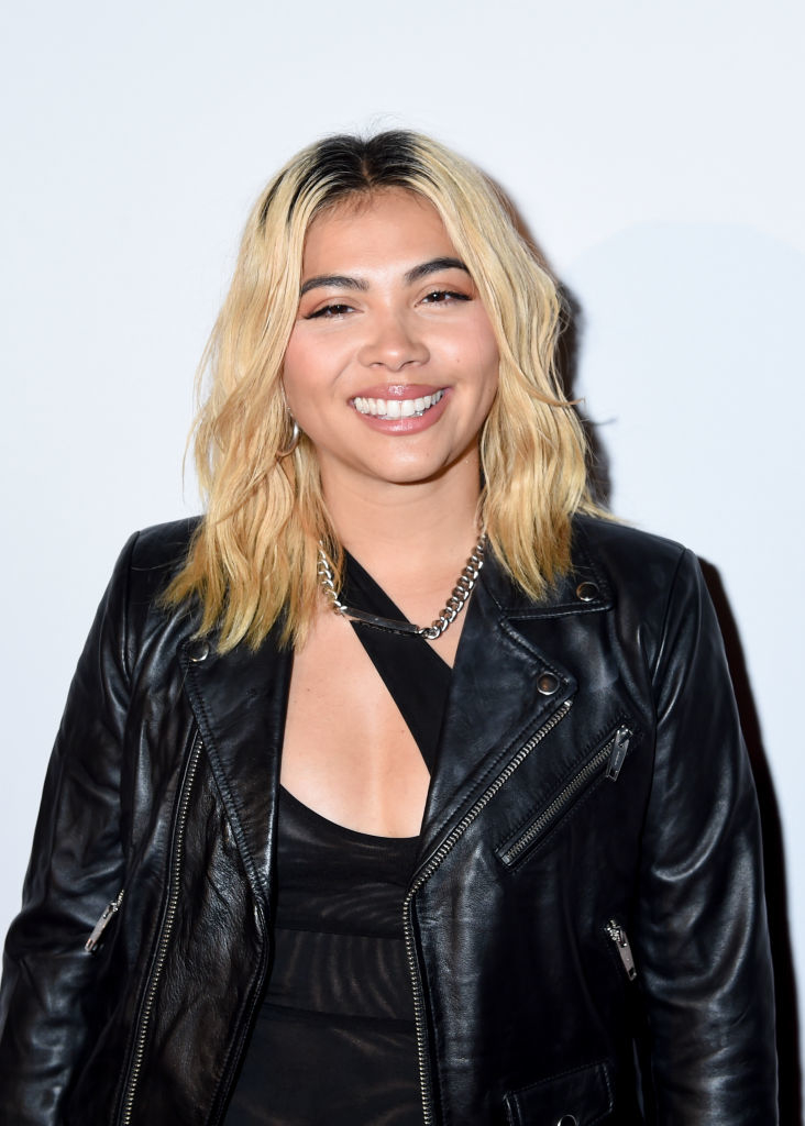 Hayley smiling, wearing leather jacket and a chain necklace