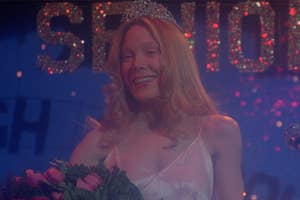 Carrie White crowned at prom, smiling with bouquet, "Seniors" sign in background