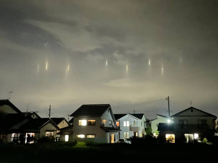 夜空に映る不思議な光の柱と住宅街の風景