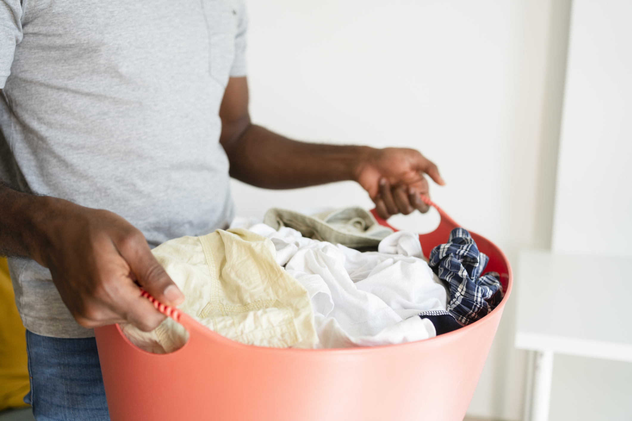 Person holding a laundry basket, focusing on shared household chores