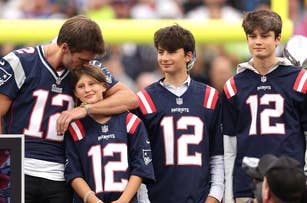 Tom Brady with three children in Patriots jerseys at a football stadium